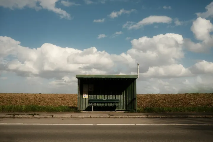 Gray and white wooden house near road under white clouds and blue sky during daytime
