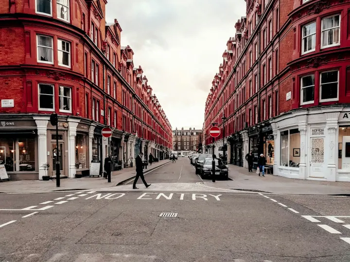 People walking on street between red concrete buildings during daytime