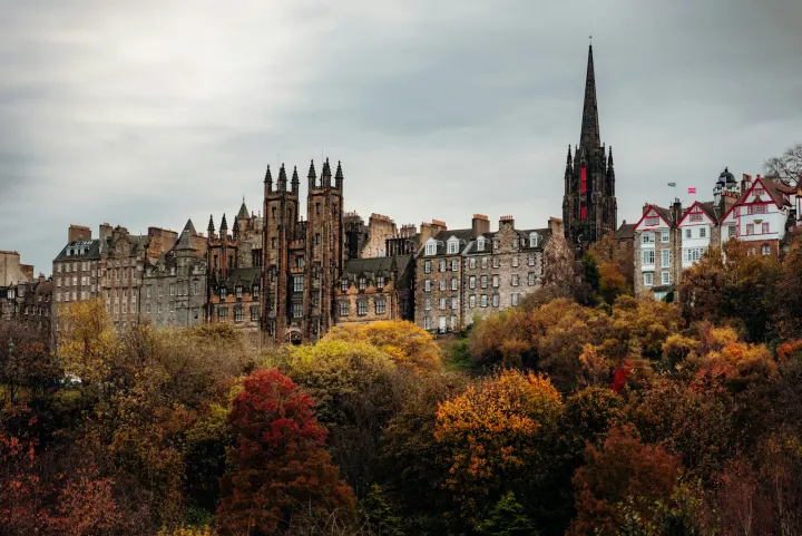 Historic buildings overlook autumn trees under a cloudy sky